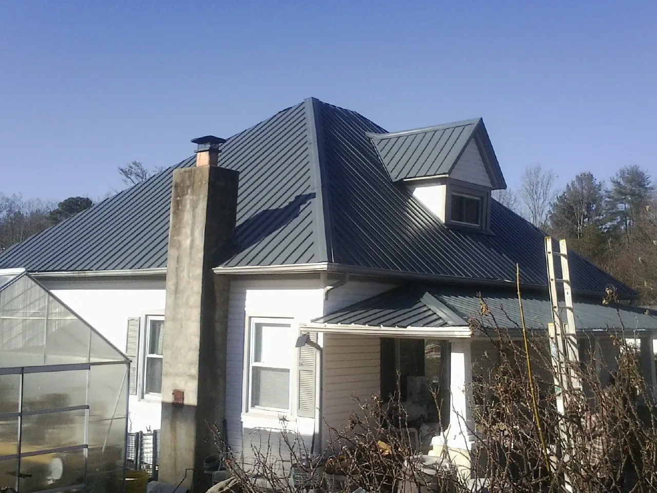 Dark blue standing seam metal roof on a white farmhouse with dormer — Slate & Tile Roof Repair by Roofing Brothers in Trout Run