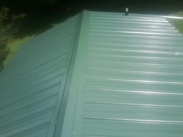 New green metal panels meeting at the ridge of a roof — Flat Roof Repair work by our crew in Trout Run