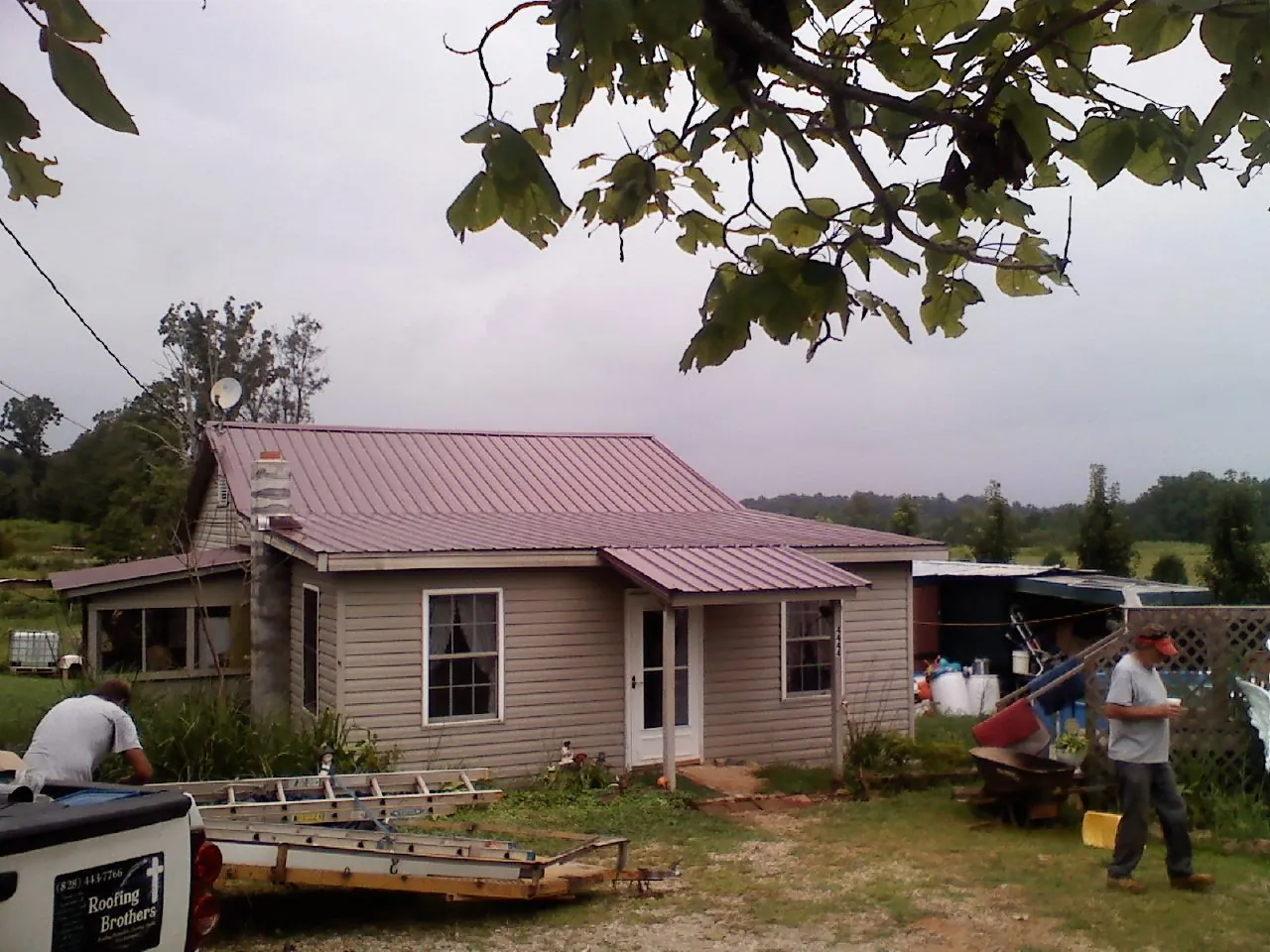 Crew finishing a mauve metal roof on a small farmhouse in Trout Run