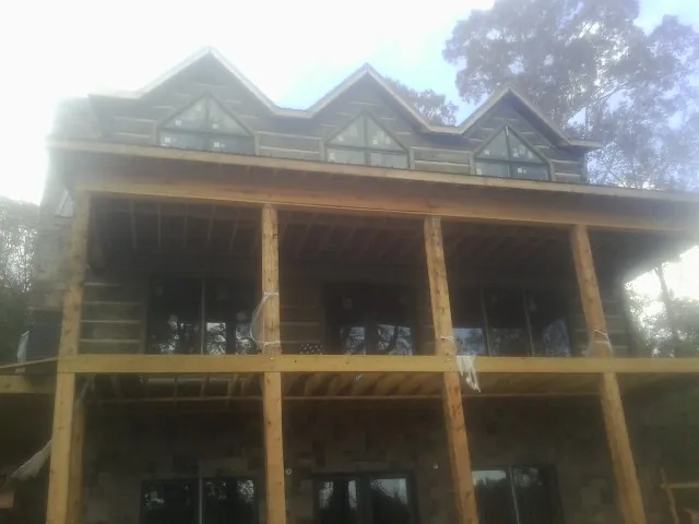 Dormers and porch framing on a large log home under construction — Roof Coating work by our crew in Trout Run