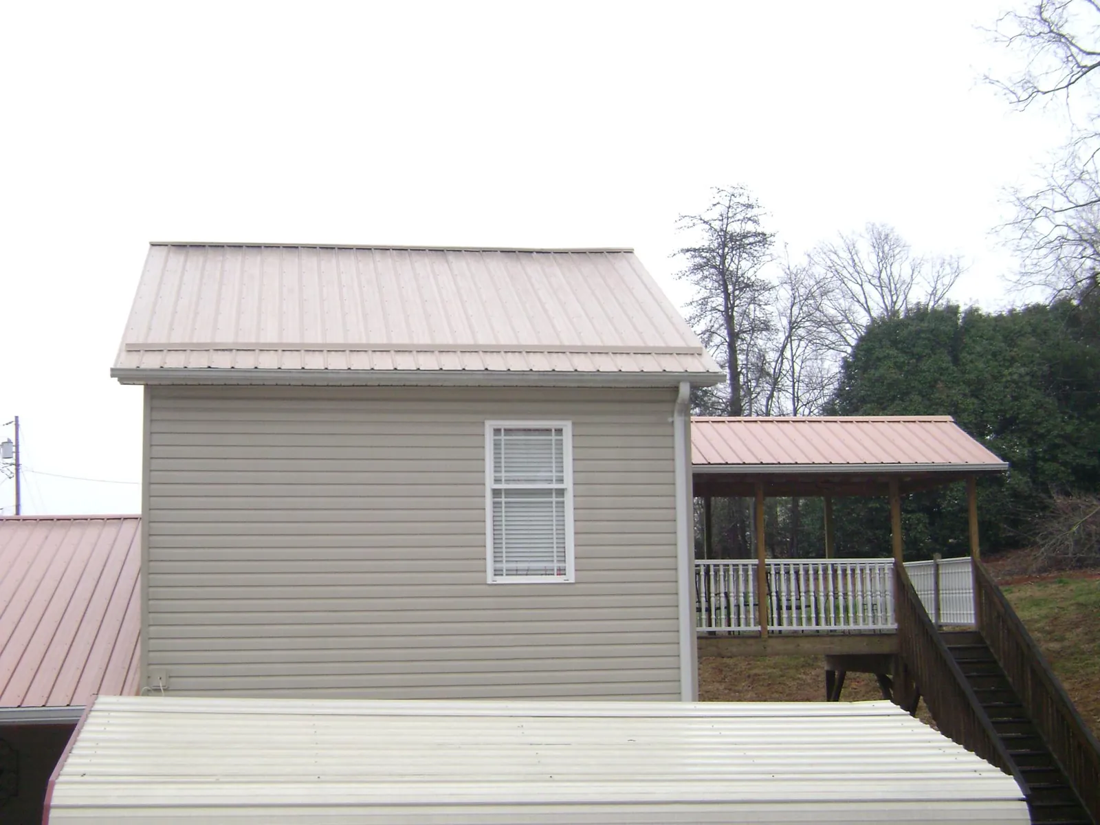 Tan metal roofs on a two story addition and attached porch, from a Roof Replacement job in Trout Run