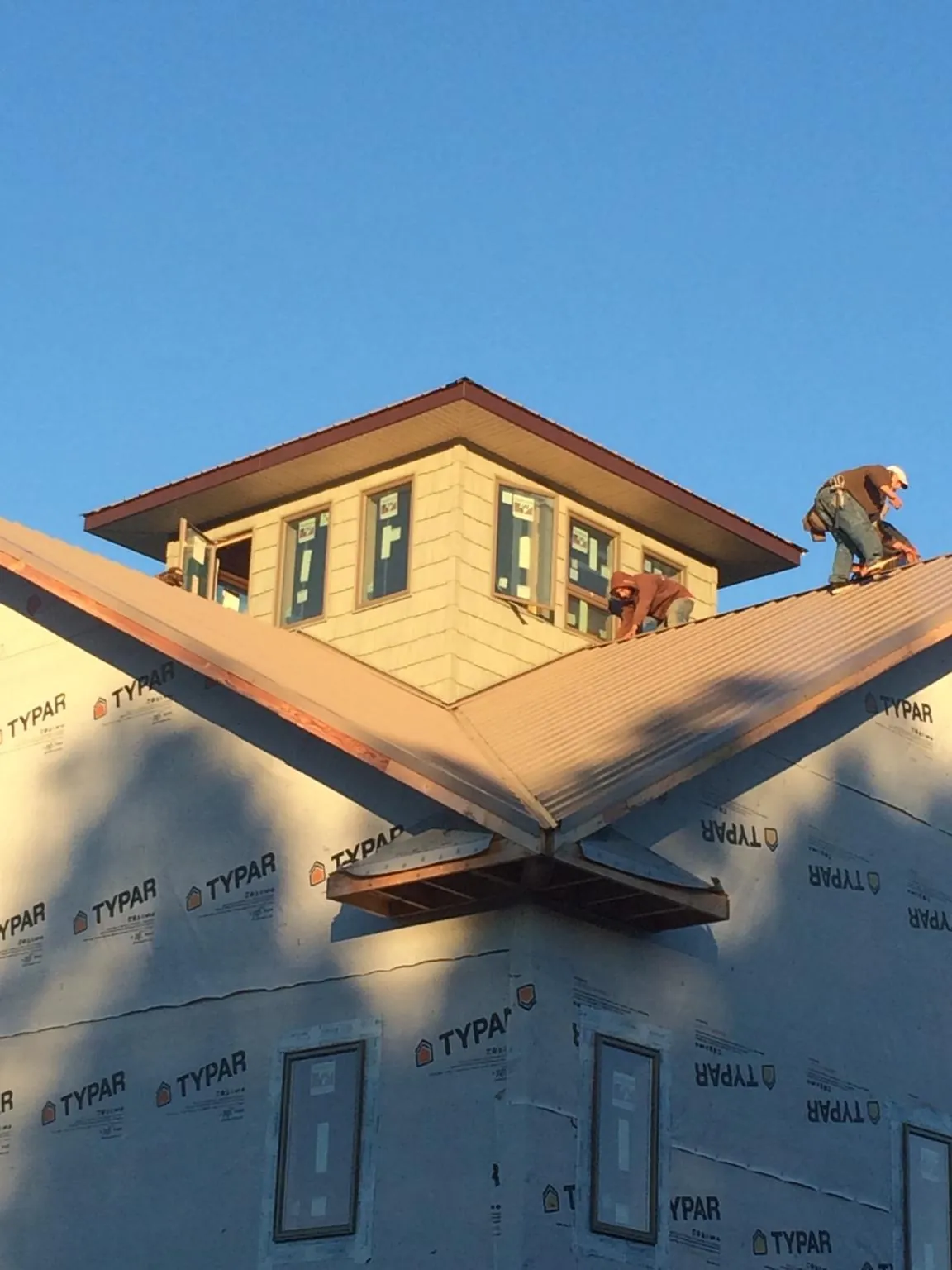 Roofers working around a rooftop cupola on a new metal roof at sunset — Roof Waterproofing in Trout Run by Roofing Brothers